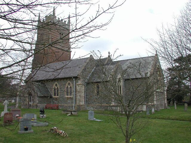 A church with a tall tower and a graveyard in front.