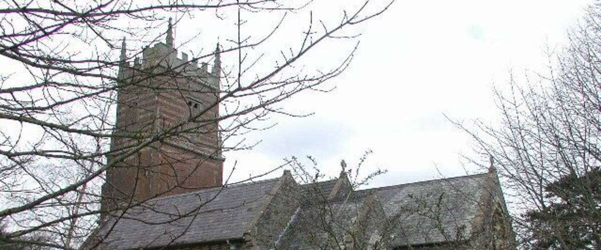 A church with a tall tower and a graveyard in front.