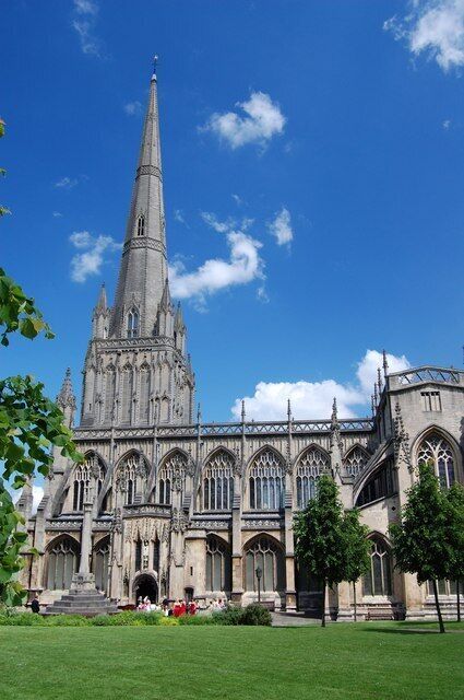 A large Gothic cathedral with a tall spire, intricate stonework, and a well-maintained lawn in front.