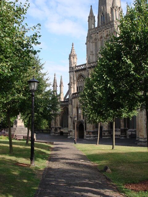 A cathedral with Gothic architecture, a pathway leading to it, and surrounding trees.