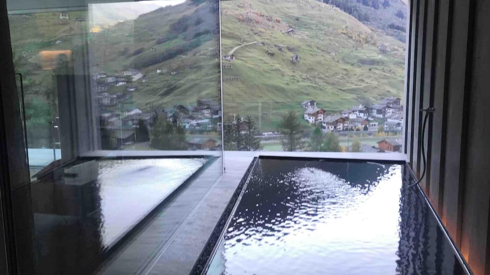 Un bâtiment moderne doté de grandes fenêtres en verre qui donnent sur un paysage vallonné parsemé de maisons.