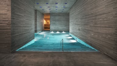 Una piscina interior moderna con paredes de madera y una fuente de luz central.