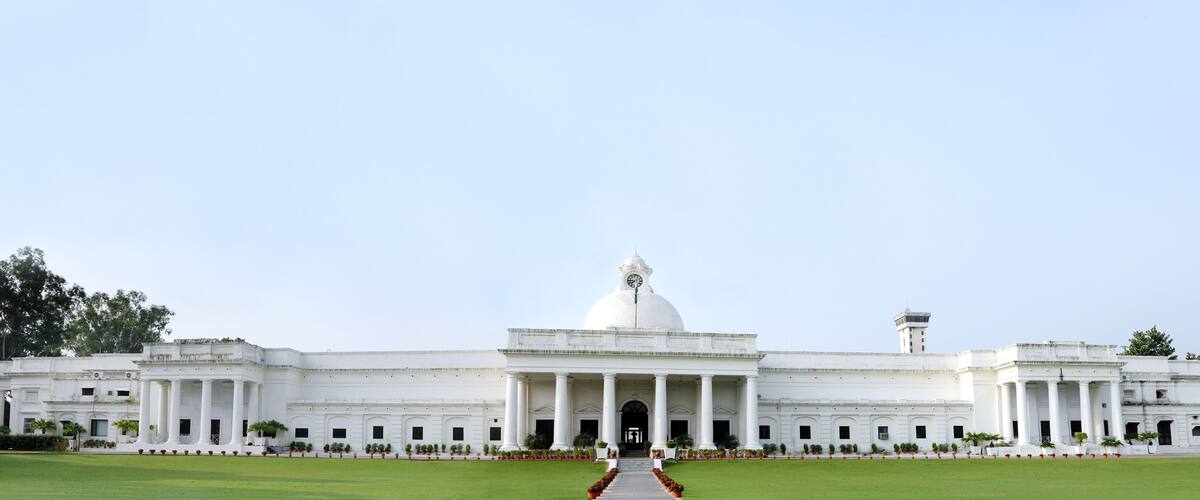 A large white building with a central dome and columns, surrounded by a well-maintained lawn and trees.