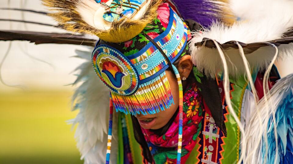 A person wearing a colorful headdress with feathers and beads.