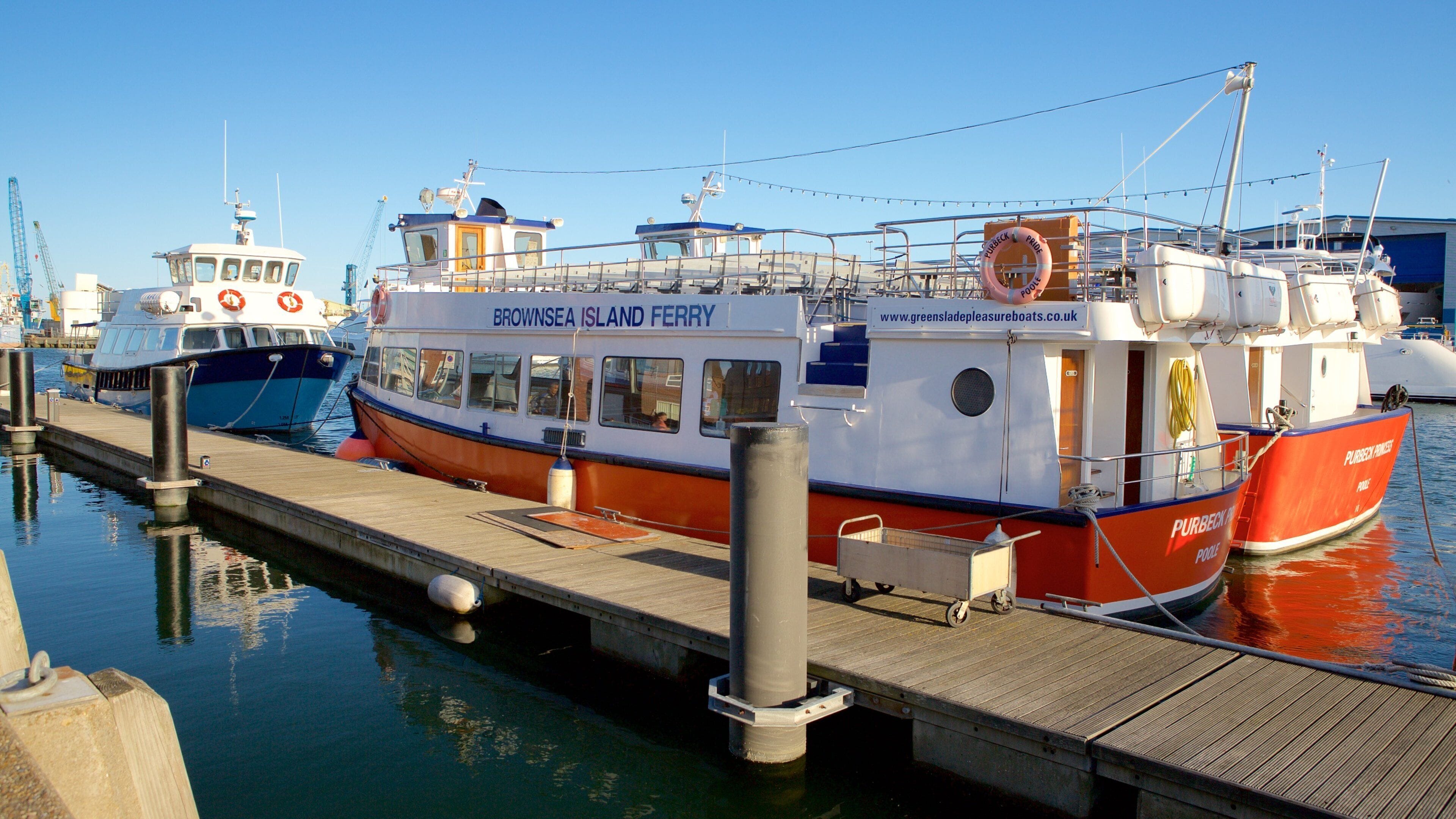 Eine Fähre liegt an einem Steg, wo weitere Boote vor Anker liegen.