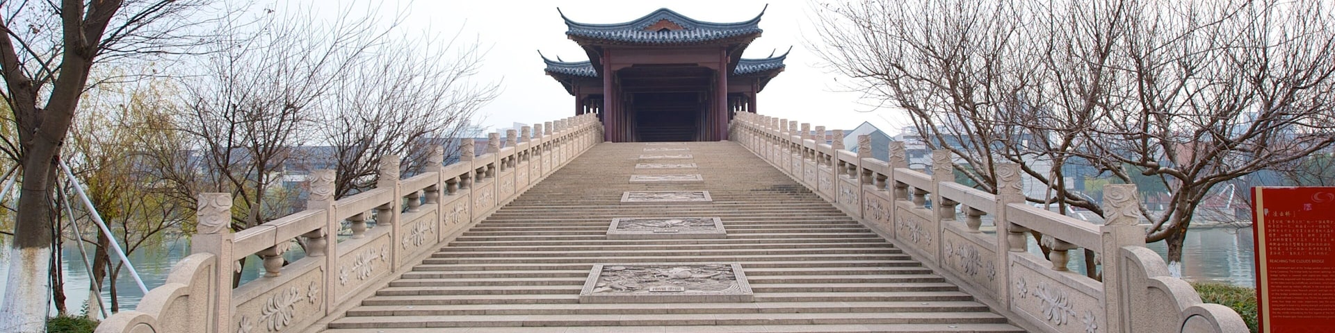 Un puente de piedra con intrincadas esculturas que conduce a una puerta tradicional china.