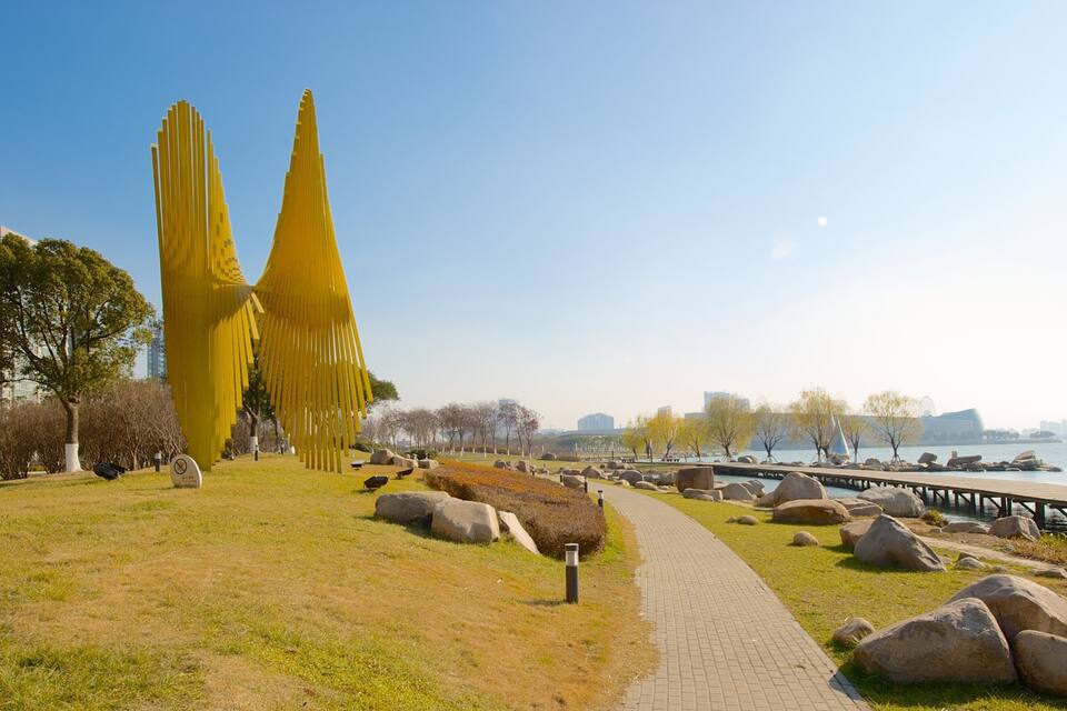 Een park met gele sculpturen, een pad en een waterkant.