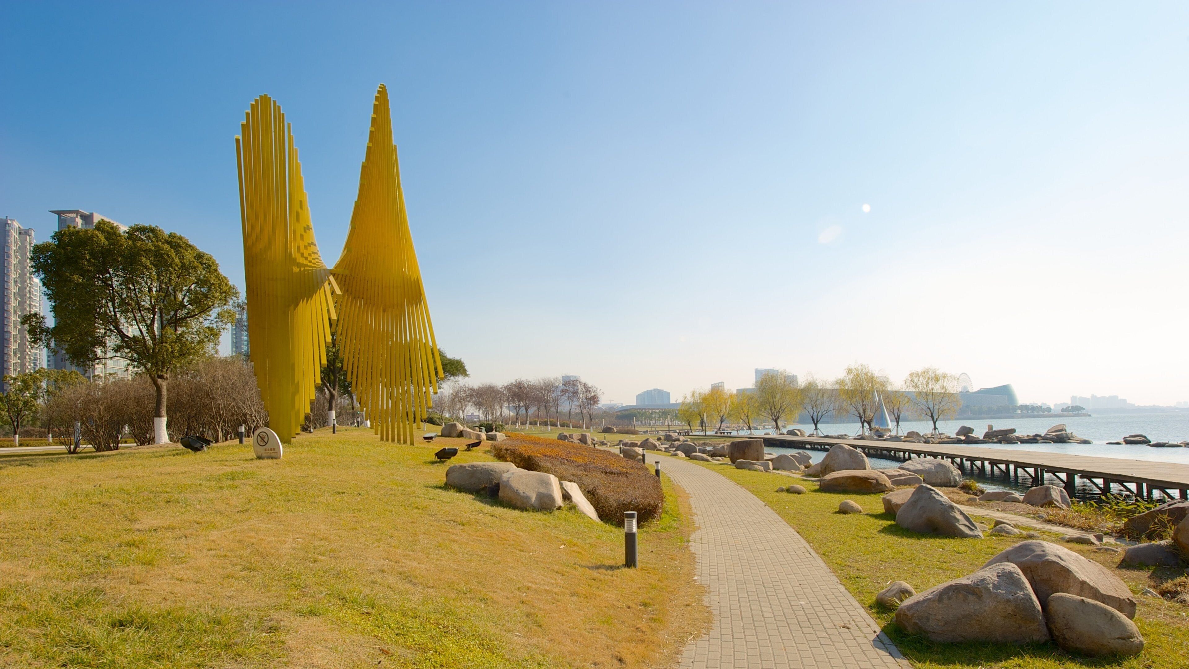 A park with yellow sculptures, a pathway, and a waterfront.