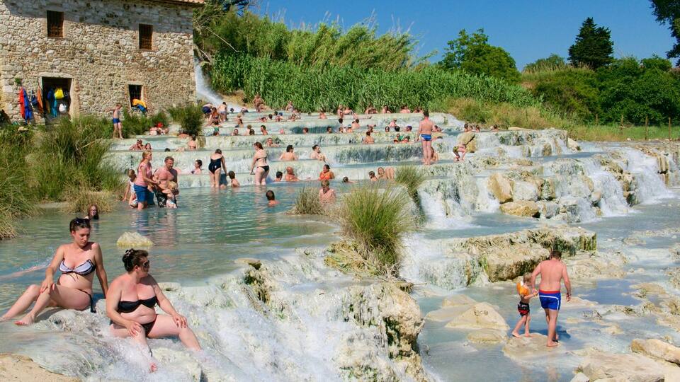A natural hot spring with multiple terraces and people enjoying the water.