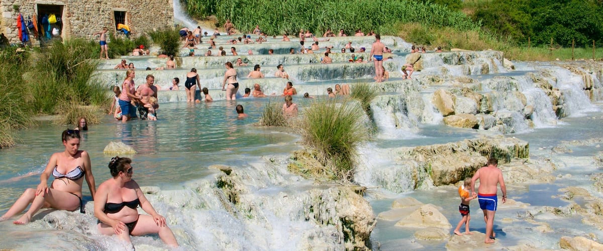A natural hot spring with multiple terraces and people enjoying the water.
