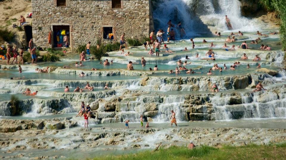 A natural hot spring area with multiple terraces and people enjoying the water.