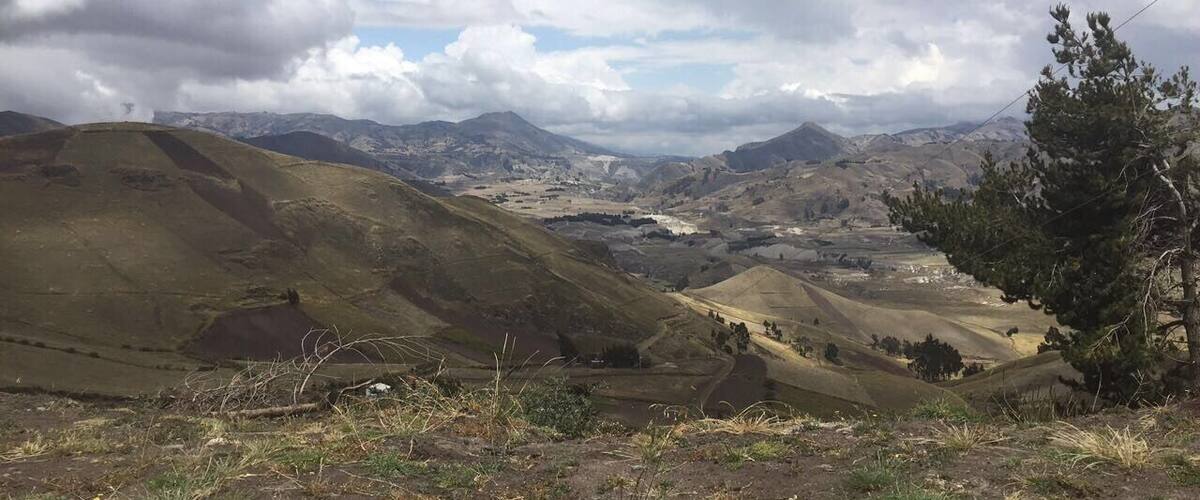 A mountainous landscape with rolling hills, a valley, and a distant town.