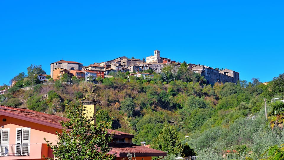 A hillside village with historic buildings and lush greenery.