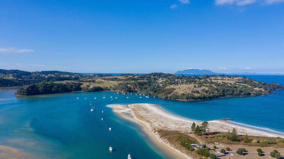 A coastal landscape with a bay, boats, and a beach.