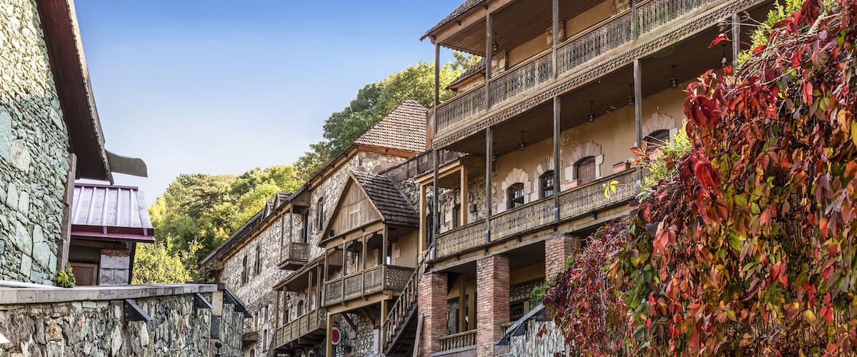 Una calle adoquinada bordeada por edificios de madera tradicionales con balcones y muros de piedra.