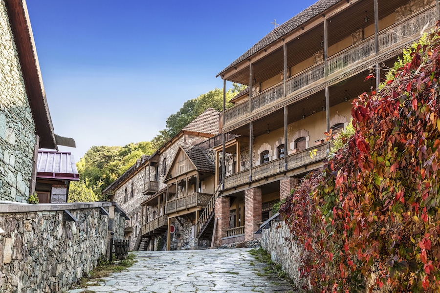 Una calle adoquinada bordeada por edificios de madera tradicionales con balcones y muros de piedra.