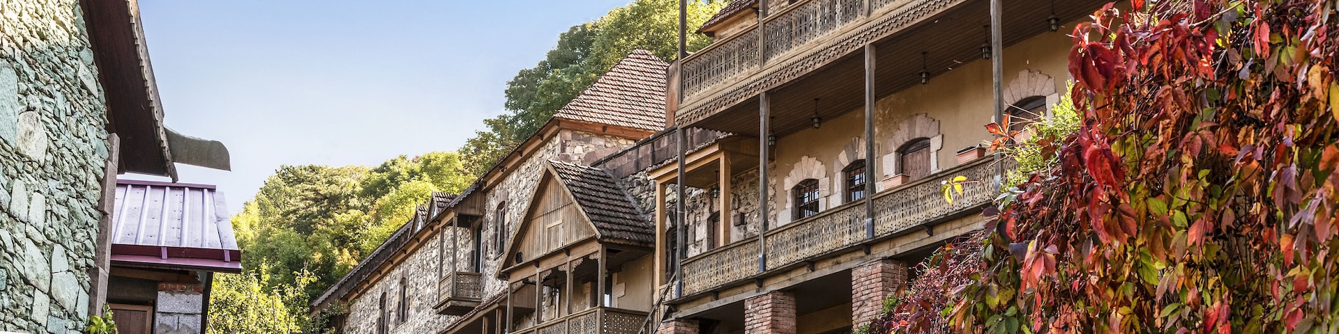 Rua de paralelepípedos ladeada por edifícios de madeira tradicionais, com varandas e paredes de pedra.