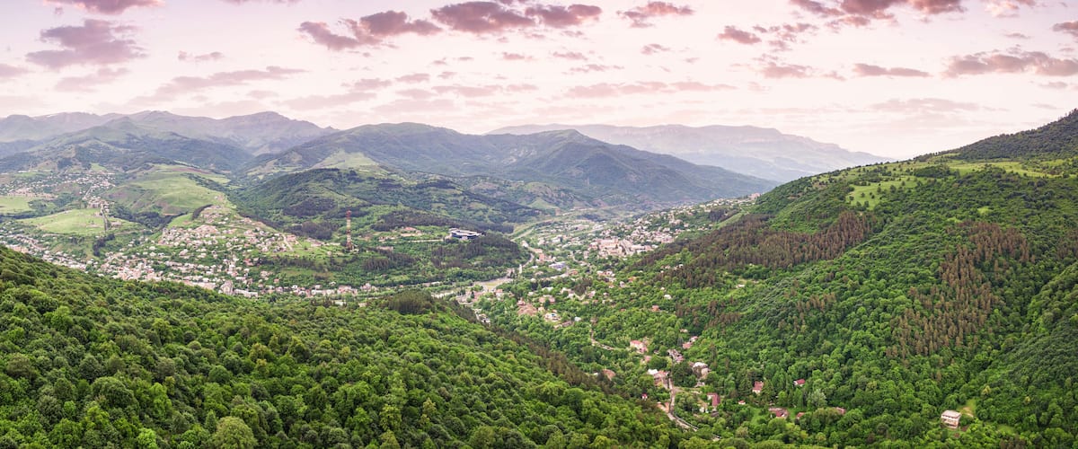 A valley with a town nestled among green hills and mountains.