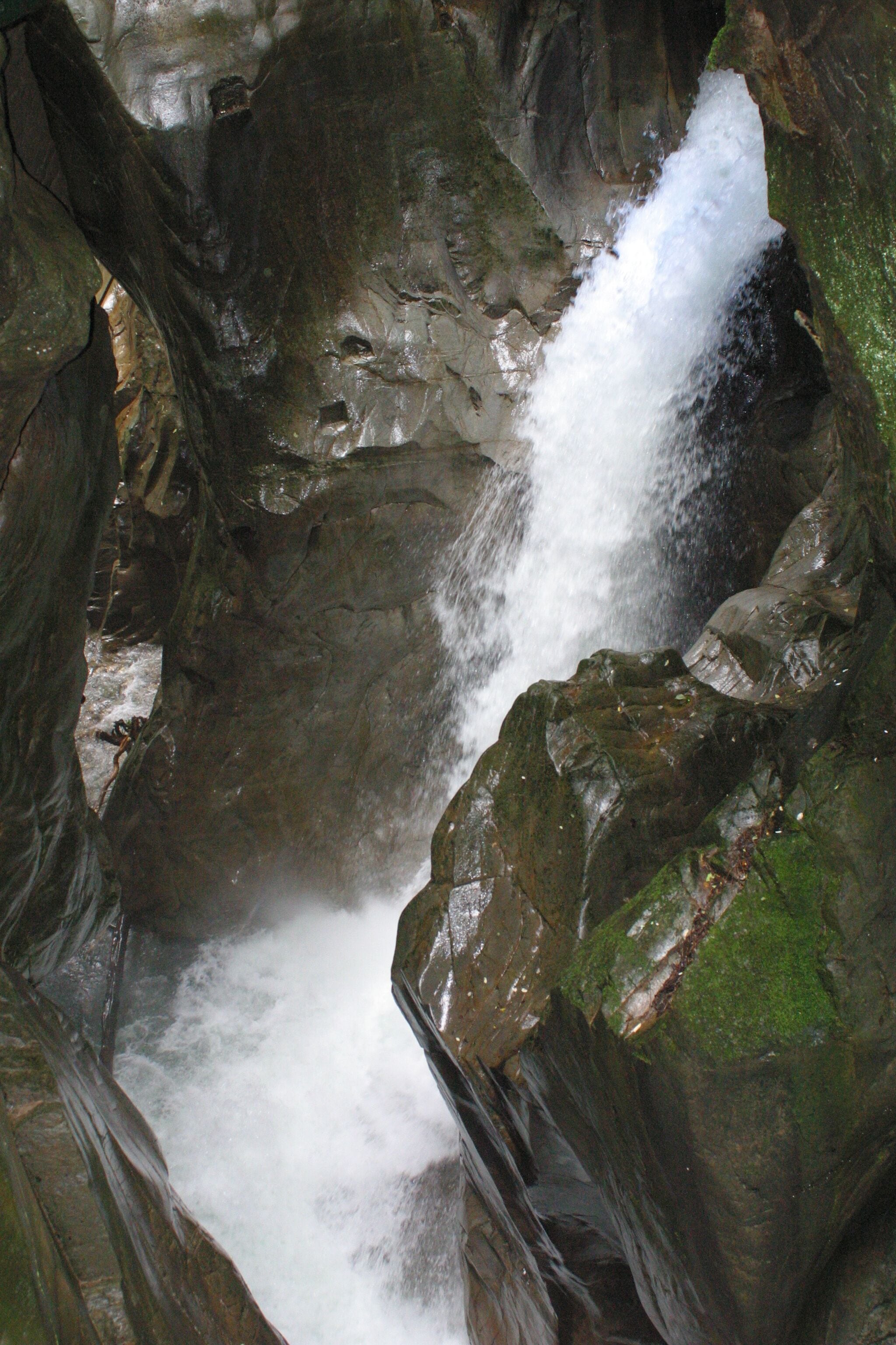 A waterfall cascading over moss-covered rocks in a rocky gorge.