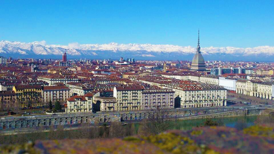 A cityscape with a prominent tower and snow-capped mountains in the background.