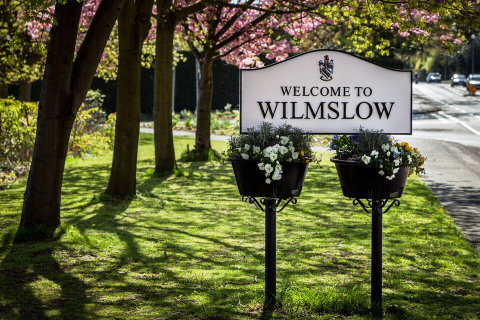 A welcome sign to Wilmslow with two flower pots on either side.