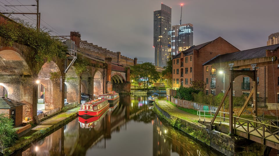 Castlefield in Manchester, UK, at night, with a modern skyscraper in the back