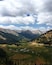 Un paisaje montañoso con un camino sinuoso, valles verdes y bosques densos.