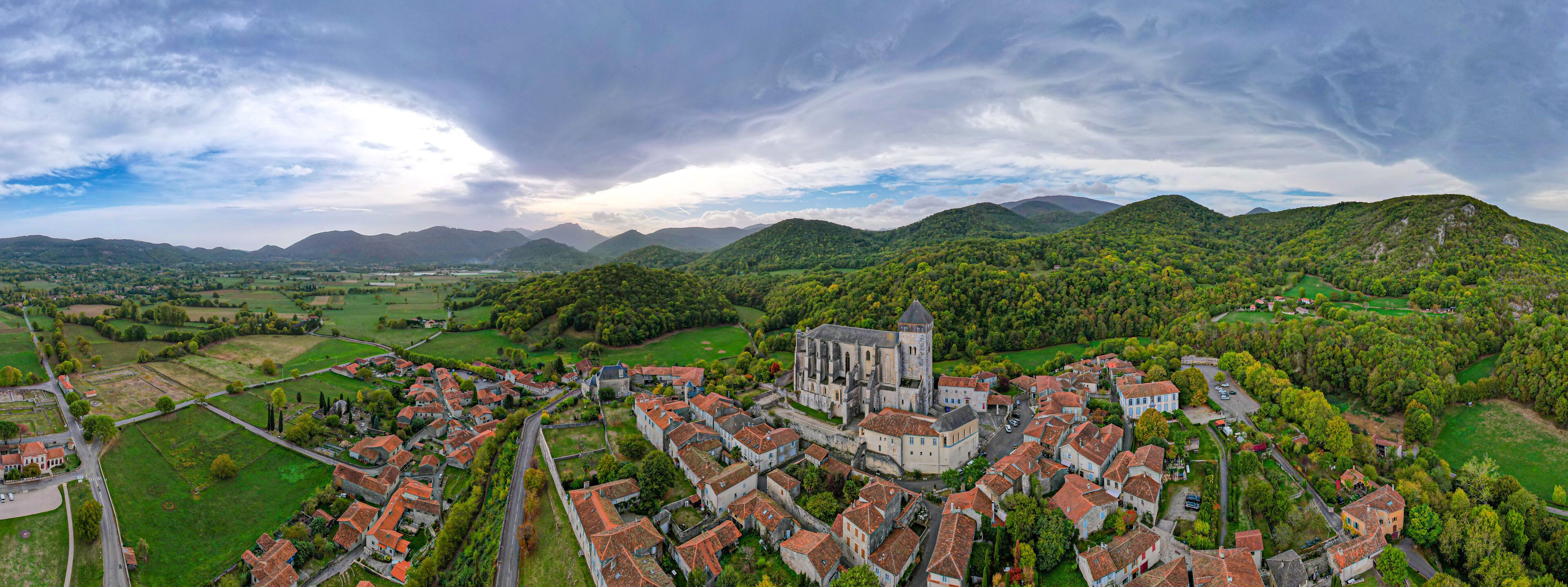 A historic town with a prominent church, surrounded by lush green hills and a river.