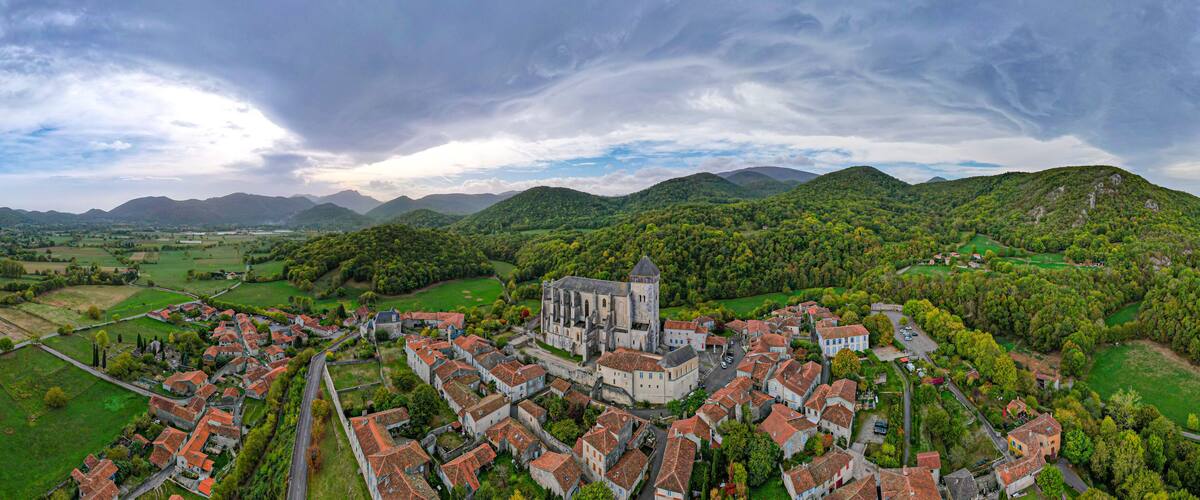 A historic town with a prominent church, surrounded by lush green hills and a river.
