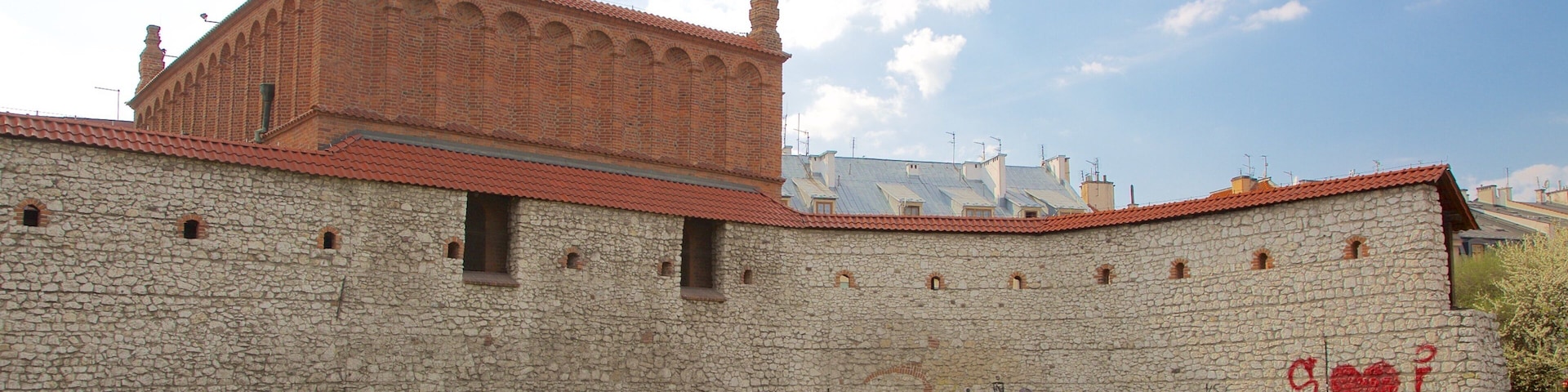Mural de pedra histórica com janelas em arco e telhado de telhas vermelhas.