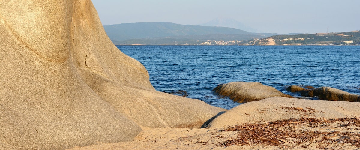 A large rock formation by the sea with a clear sky.