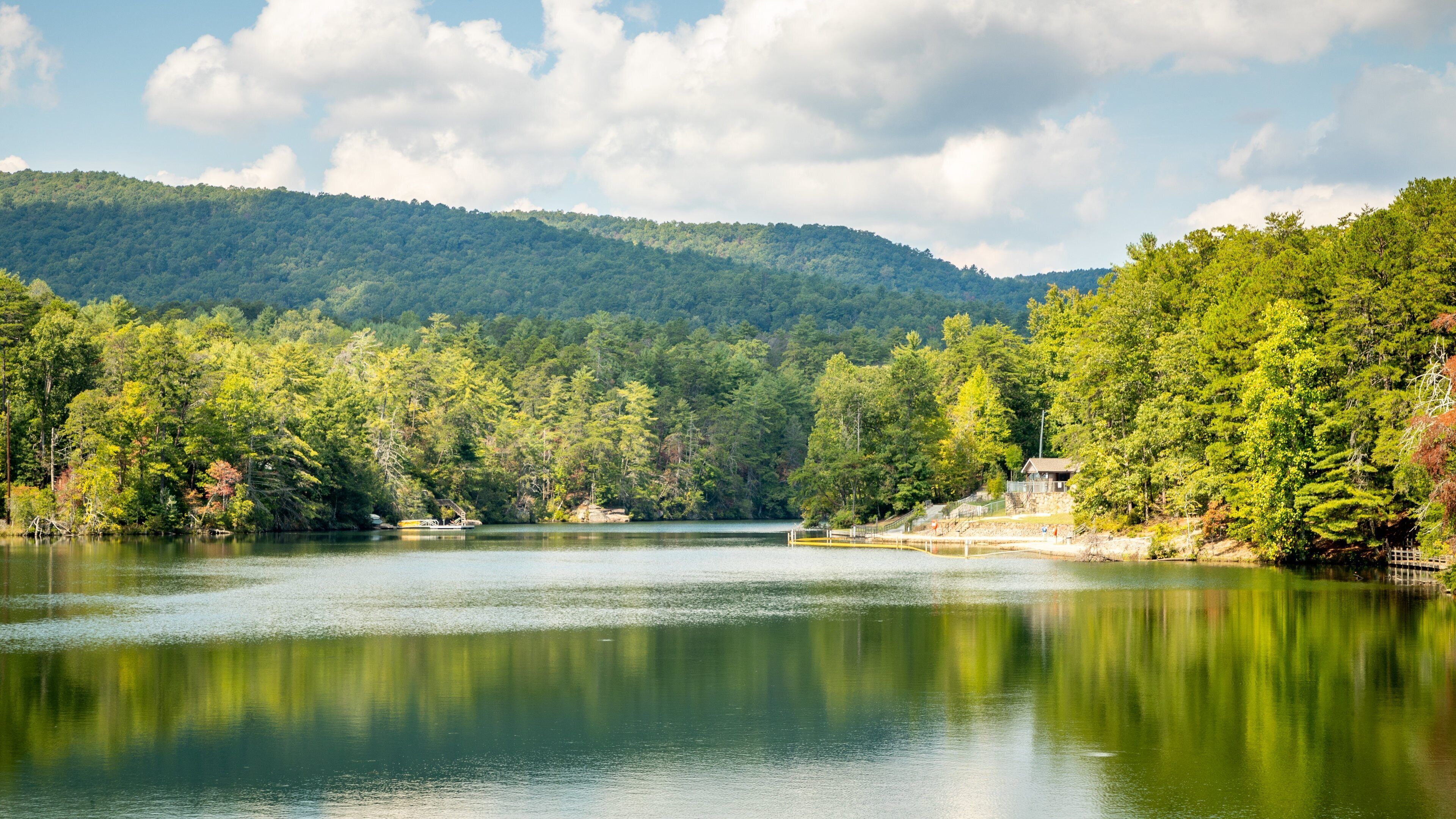 A calm lake surrounded by dense forest and a mountain in the background.