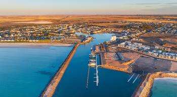 An aerial view of a coastal town with a marina, a lighthouse, and a large body of water.