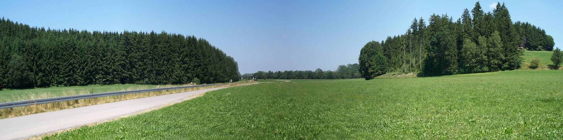 Trompetentälchen bei Schwenden, Bad Grönenbach, Landkreis Unterallgäu. Erfasst als Geotop "Ziegelberger Trompetentälchen", Geotop Nr. 778R003. Während der Rückzugsphase des Gletschers entsteht zwischen Eisrand und Endmoräne ein Stausee, der zu gegebener Zeit an der tiefsten Endmoränenstelle überläuft. Die Wassermassen schneiden sich aufgrund des hohen Gefälles tief in den Endmoränenabschnitt ein. Das Foto zeigt das Tälchen in Blickrichtung Norden, d.h. in die Richtung, in die das Wasser am Ende der letzten alpinen Eiszeit (Würm) abfloss. Dieses Trompetentälchen ist eine große Rarität, weil es im Urzustand (bis auf omnipräsente Verwitterung) konserviert wurde, da die entstehende "Iller" bereits kurz nach dem Durchbruch ihr neues Flussbett fand.