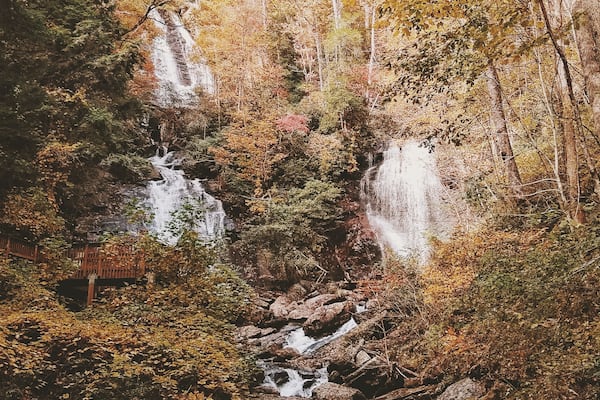 Ein Wasserfall stürzt über Felsen in einem bewaldeten Gebiet mit Herbstlaub.