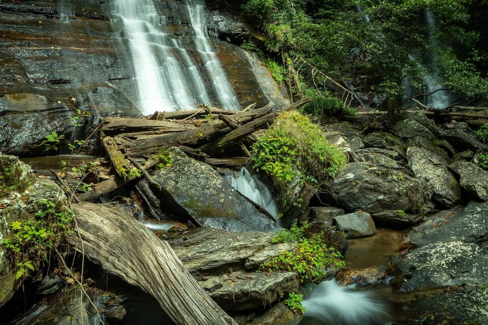 Ein Wasserfall stürzt über Felsen in einem bewaldeten Gebiet.