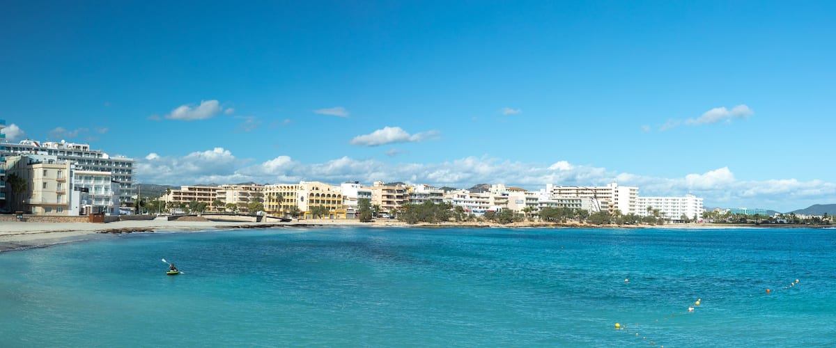 A coastal resort with a beach, clear blue waters, and a row of hotels.