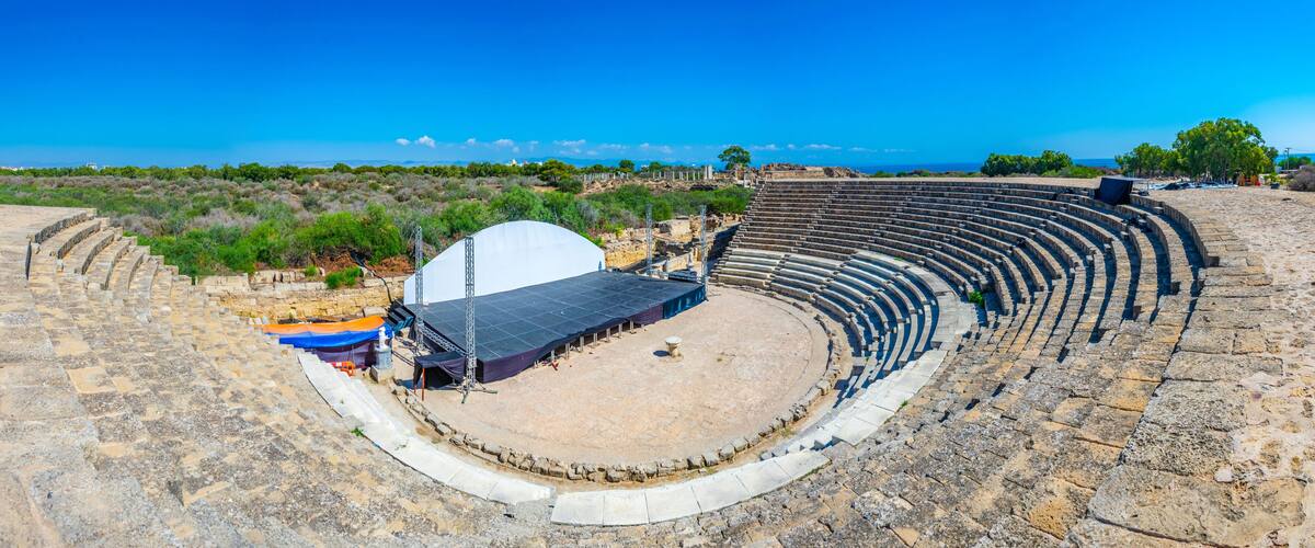 An ancient amphitheater with stone seating and a stage area.