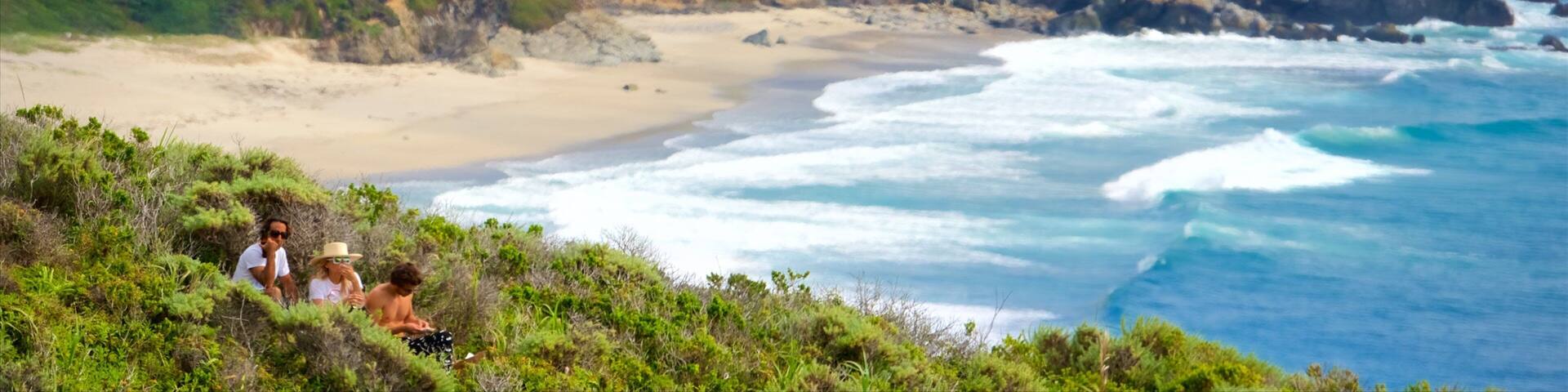 A coastal landscape with cliffs, a beach, and ocean waves.