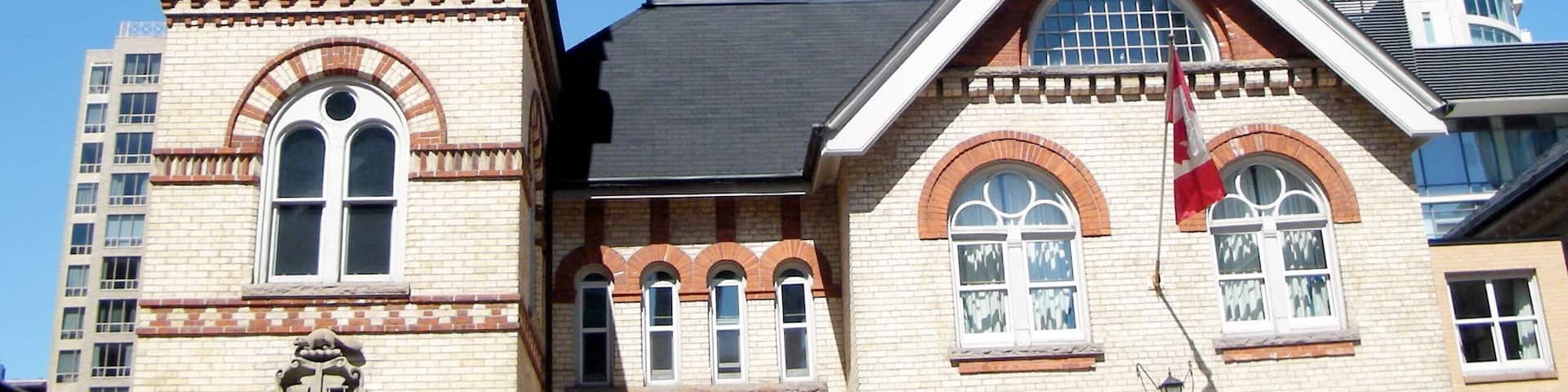 A historic building with a clock tower, arched windows, and a prominent flag.