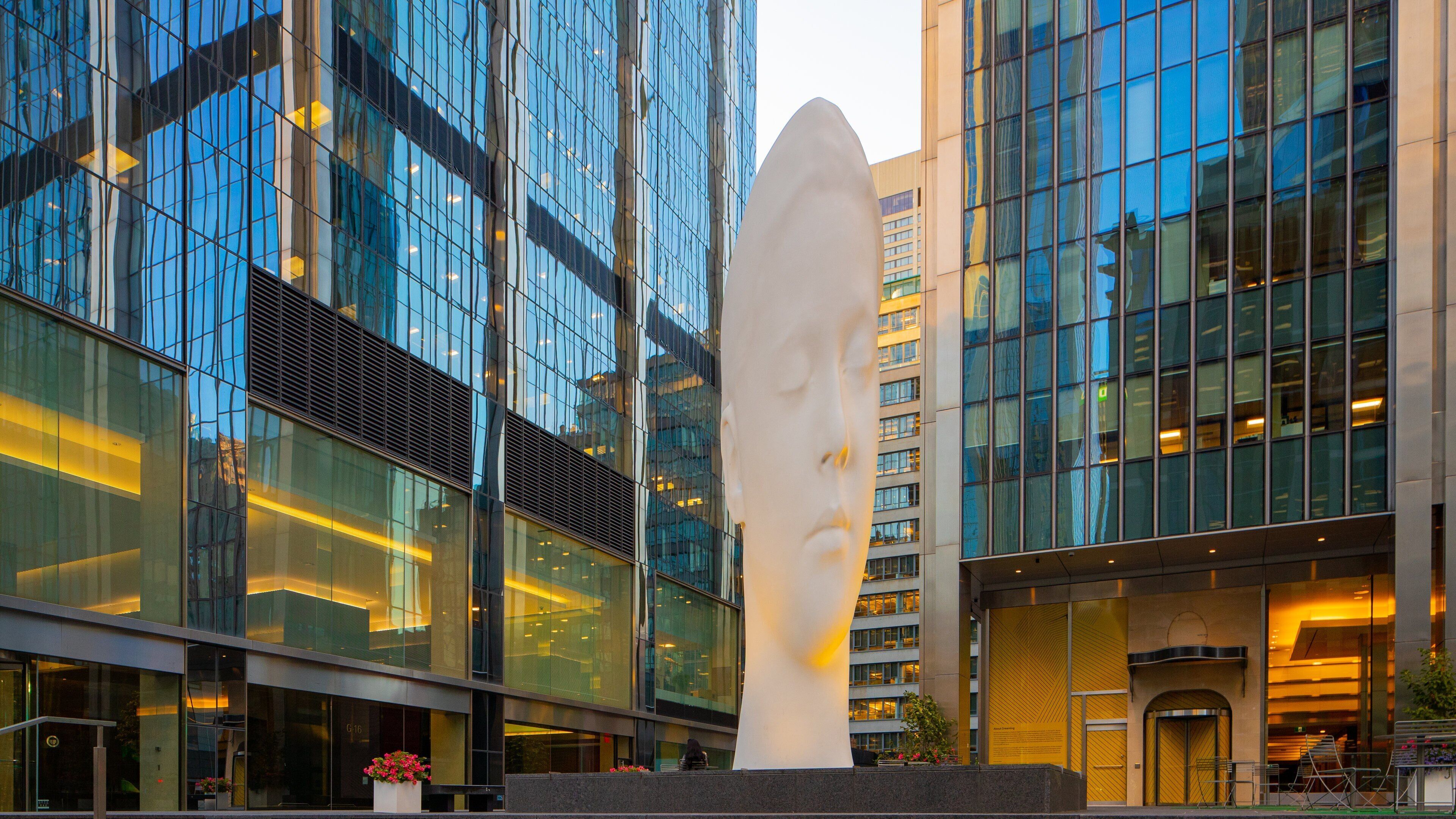 Un moderno edificio de vidrio con una gran escultura en su fachada.