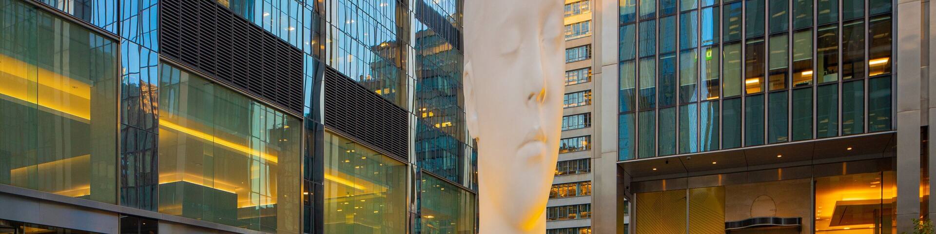A modern glass building with a large sculpture in front.