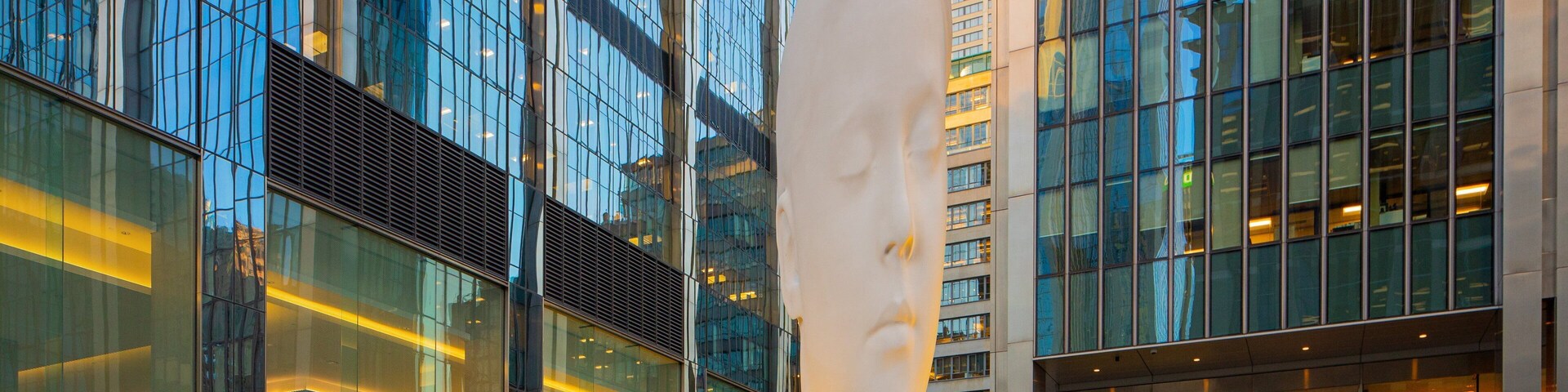 Un moderno edificio de vidrio con una gran escultura en su fachada.