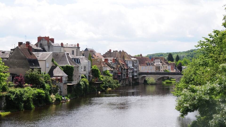 A river with houses on one side and a bridge in the distance.