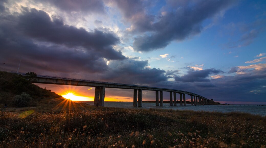 Sunset under the bridge to Noirmoutier, France, with frozen fast-moving clouds