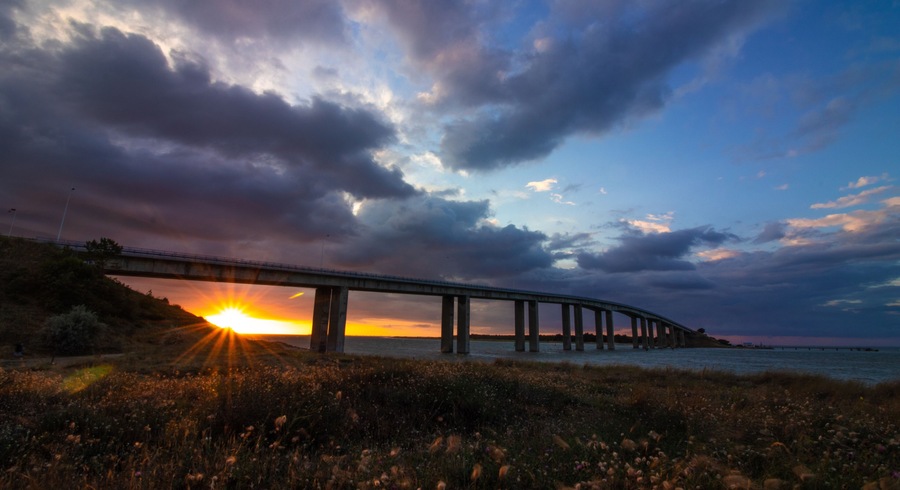 Sunset under the bridge to Noirmoutier, France, with frozen fast-moving clouds