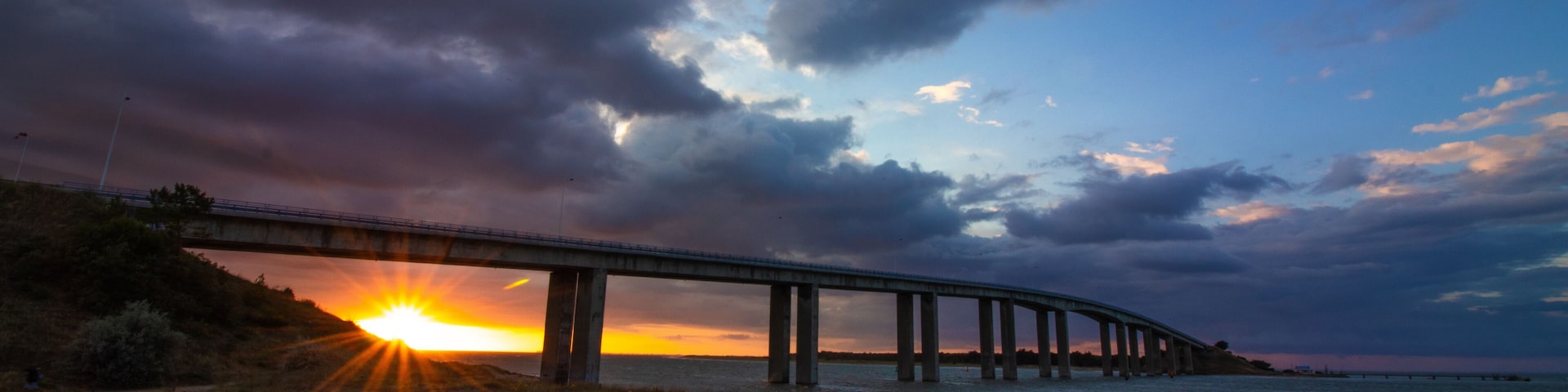 Sunset under the bridge to Noirmoutier, France, with frozen fast-moving clouds