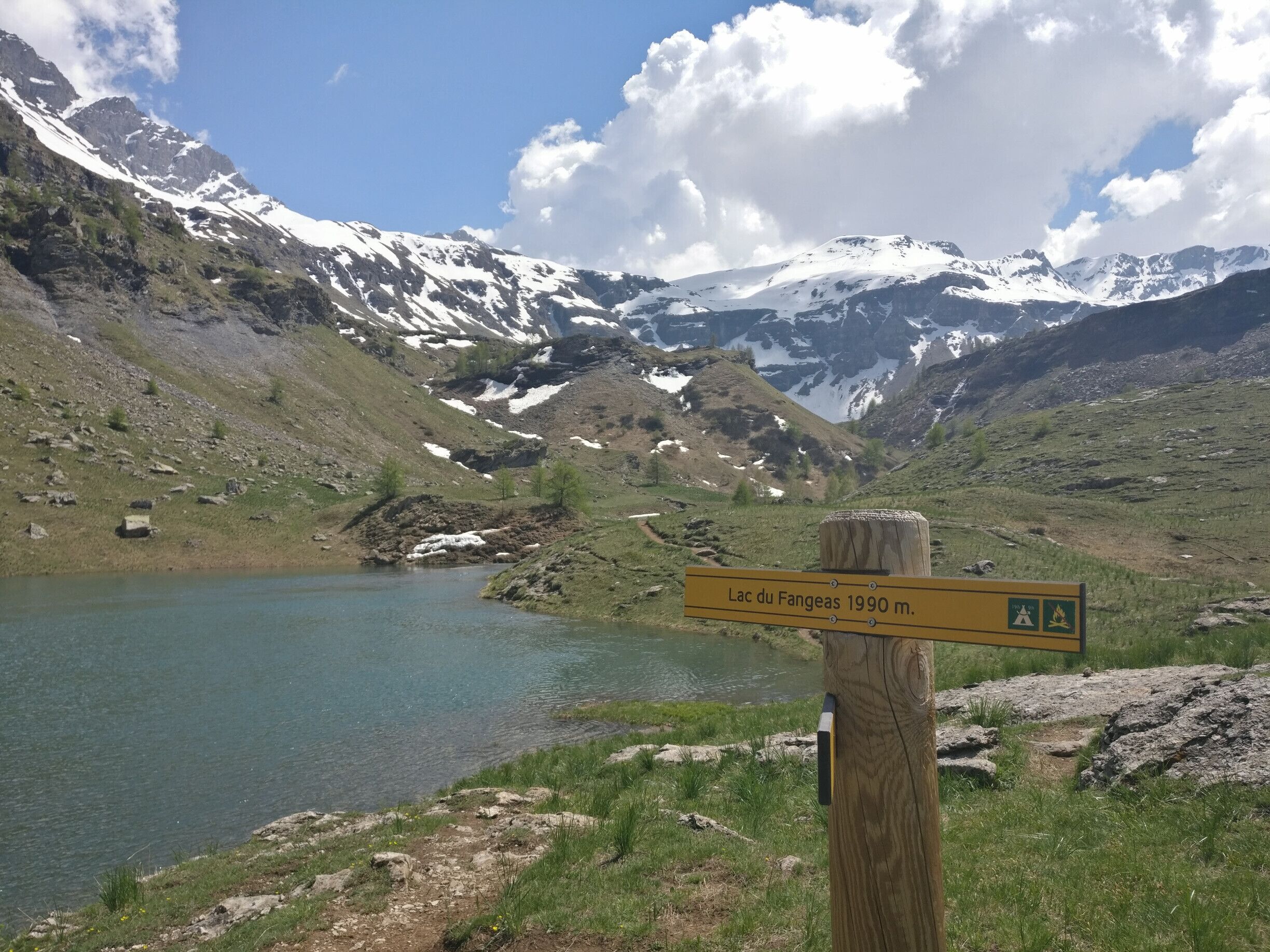 A mountain landscape with a lake and a sign indicating Lac du Fangeas 1990 m.