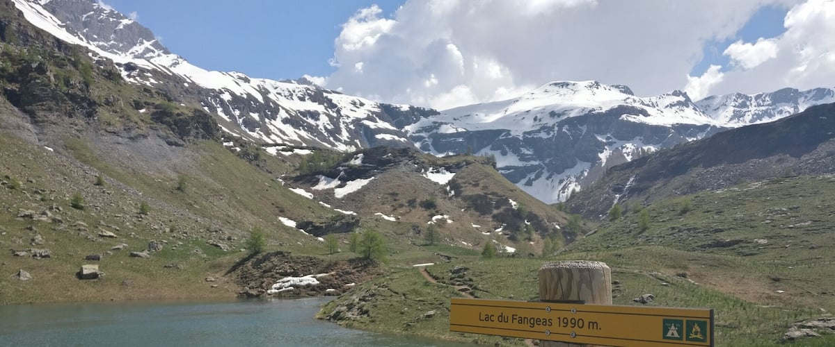 A mountain landscape with a lake and a sign indicating Lac du Fangeas 1990 m.
