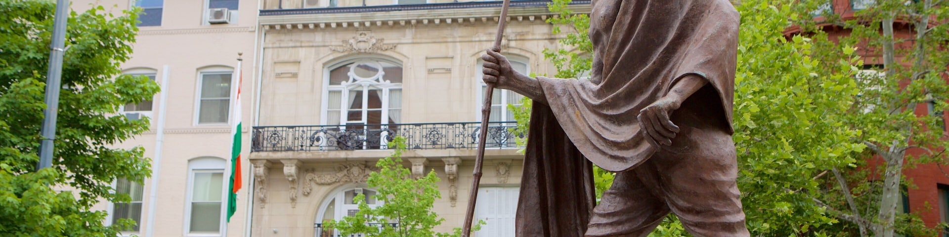 Uma estátua de um homem com um cajado em frente a um edifício com arquitetura elaborada.